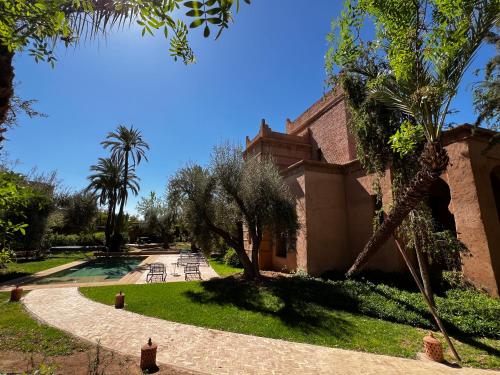 a building with trees and a walkway in a park at Villa kasbah de luxe, piscine et jacuzzi chauffés, jardin tropical in Marrakech