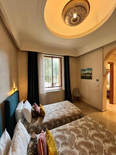 a hotel room with two beds and a window at Villa kasbah de luxe, piscine et jacuzzi chauffés, jardin tropical in Marrakech
