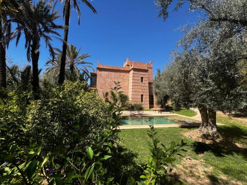 a house with a swimming pool and palm trees at Villa kasbah de luxe, piscine et jacuzzi chauffés, jardin tropical in Marrakech
