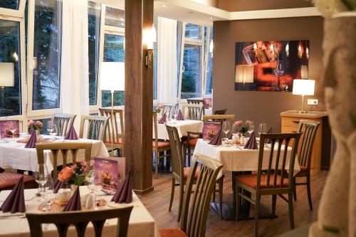 a restaurant with white tables and chairs and windows at Parkhotel Helene in Bad Elster