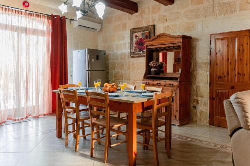 a kitchen with a table with chairs and a refrigerator at Villa Savona Sleeps 7 with Private Pool in Xagħra