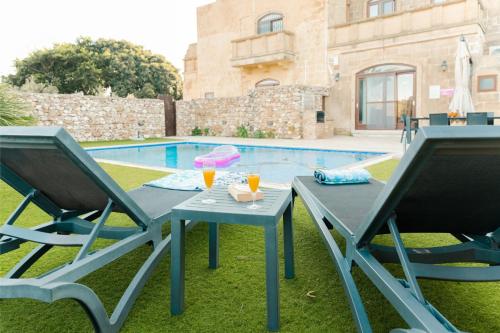 a table and two chairs next to a pool at Villa Savona Sleeps 7 with Private Pool in Xagħra