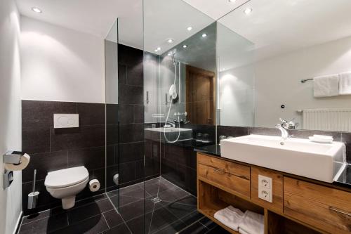 a bathroom with a sink and a toilet and a mirror at ROBINSON ALPENROSE Zürs in Zürs am Arlberg