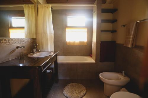 a bathroom with a sink and a toilet and a tub at Hermosa Casa cerca del Teleférico Cerro Otto in San Carlos de Bariloche