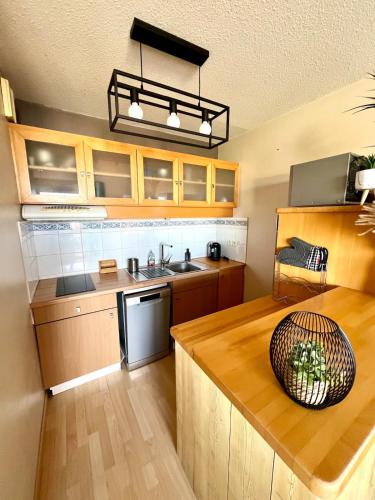 une cuisine avec des armoires en bois et une table en bois dans l'établissement Le Corsaire - Appartement spacieux avec terrasse, à Aytré