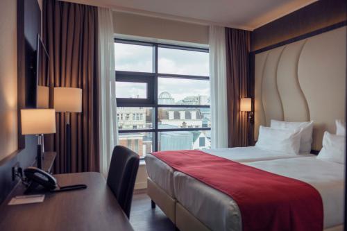 a hotel room with a bed and a large window at PLAZA Premium Den Haag City Center in The Hague