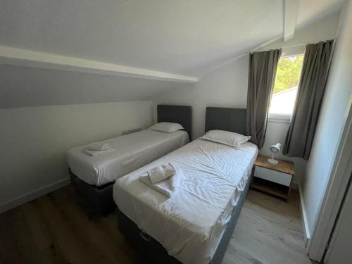 deux lits dans une petite pièce avec une fenêtre dans l'établissement Mini villa avec jardin Cala Rossa - Porto Vecchio, à Lecci