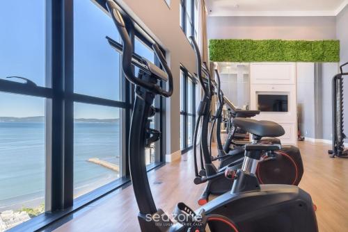 a gym with cardio equipment and a view of the ocean at MHFA - Studios em Prédio Luxuoso com Vista Mar in Itapema