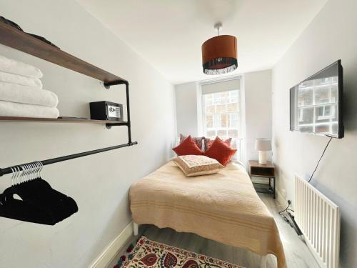 a small bedroom with a bed with red pillows at Soho Guest House Room 2 in London