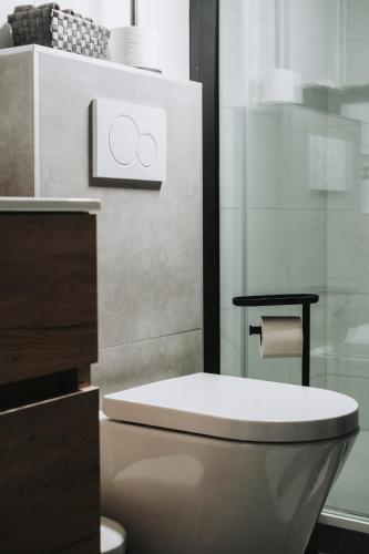 a bathroom with a toilet and a glass shower at Huisje Mezengroet in Lanaken
