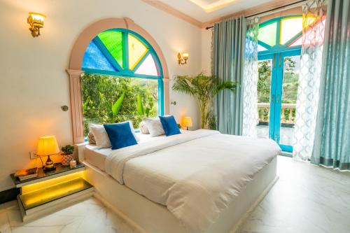 a bedroom with a large bed with a large window at Bhagvatam by the Ganges in Shivpuri