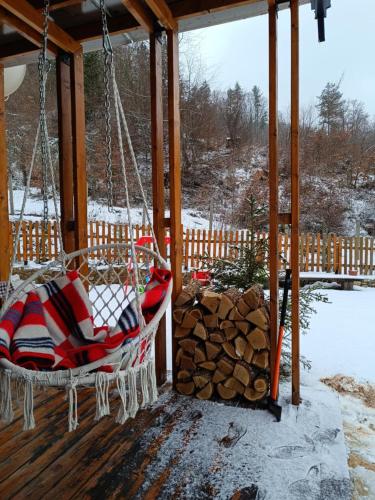 a swing on a porch with a pile of logs at Wooden Mountain Villa in Berovo