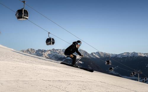 a person skiing down a snow covered slope with a ski lift at Hotel Lanerhof active/spa/balance in San Lorenzo di Sebato