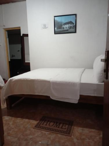 a bed in a room with a picture on the wall at The Mist Holiday Bungalow in Haputale