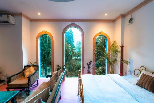 a bedroom with a bed and large windows at Bhagvatam by the Ganges in Shivpuri