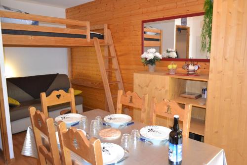 - une table à manger et des chaises dans un dortoir doté de lits superposés dans l'établissement Les 3 vallées, à Orelle