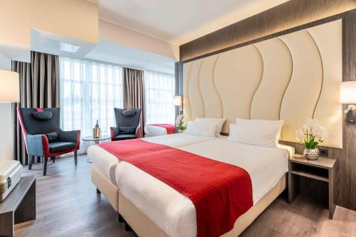 a hotel room with a large bed with a red blanket at PLAZA Premium Den Haag City Center in The Hague