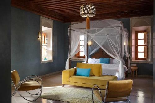 a bedroom with a bed and a yellow chair at Daba Riads in Marrakech