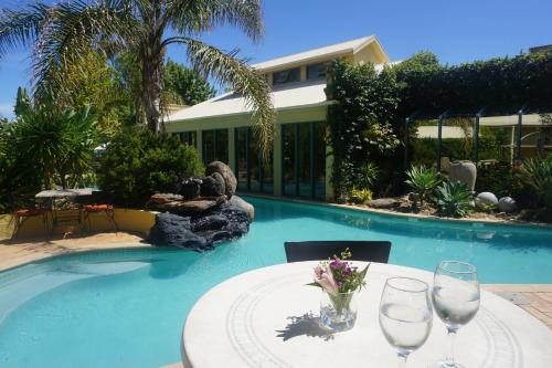 a table with wine glasses sitting next to a swimming pool at Madison Spa Motel - Adults Only in Moama