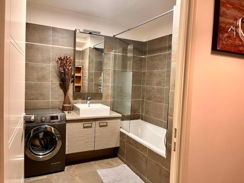 une salle de bain avec une machine à laver et un lavabo dans l'établissement La Défense Panoramic Terrace and Parking, à Courbevoie