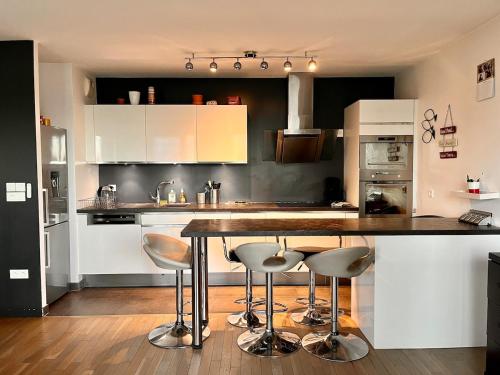 une cuisine avec des armoires blanches et un comptoir avec des tabourets dans l'établissement La Défense Panoramic Terrace and Parking, à Courbevoie
