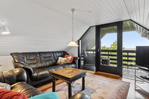 a living room with a leather couch and a table at Feriehus 1084 in Ulfborg