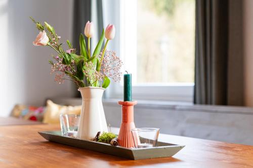 a tray with vases and flowers on a table at Forellenhof Wald- und Wiesenquartier in Bad Berleburg