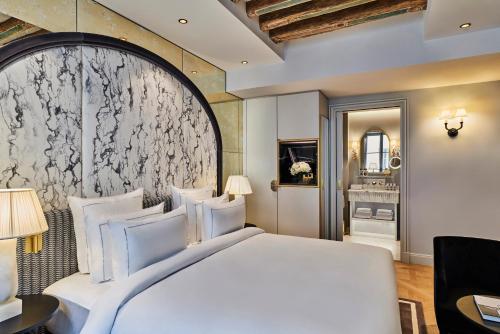 a bedroom with a large white bed and a mirror at Maison Barrière Vendôme in Paris