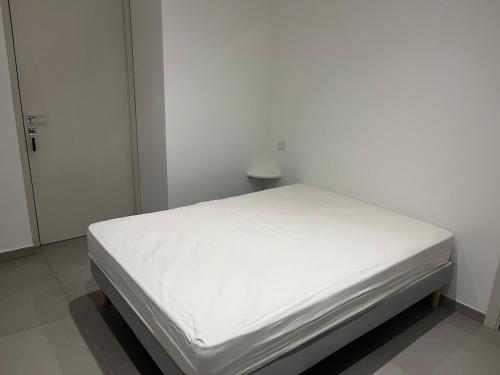 Ce lit se trouve dans un dortoir blanc doté d'un matelas blanc. dans l'établissement Appartement proche de la plage, à Santa-Lucia-di-Moriani