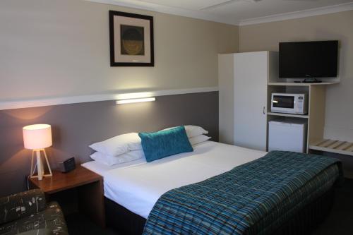 a hotel room with a bed and a flat screen tv at Motel Northview Mackay in Mackay