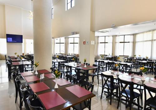 a dining room with tables and chairs and windows at Hotel Rainha dos Apóstolos in Aparecida