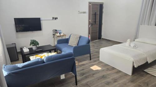 a living room with two blue chairs and a bed at Roghan Hospitality Inn in Al Ḩamrāʼ