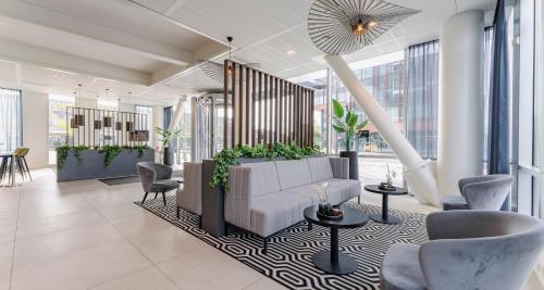 a lobby with a couch and chairs and windows at PLAZA Premium Almere in Almere
