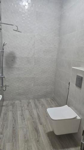 a white bathroom with a toilet and a sink at Roghan Hospitality Inn in Al Ḩamrāʼ
