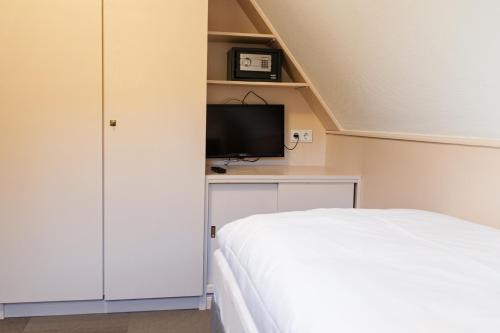 a bedroom with a bed and a flat screen tv at Forellenhof Wald- und Wiesenquartier in Bad Berleburg