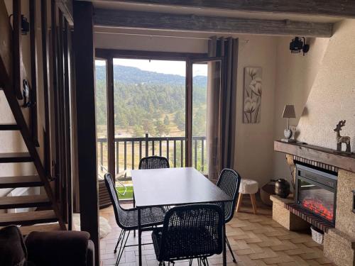 - une table et des chaises dans le salon doté d'une cheminée dans l'établissement Duplex Vue Montagne au Calme, à Gréolières