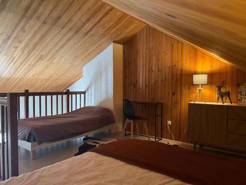- une chambre avec des murs en bois, un lit et un bureau dans l'établissement Duplex Vue Montagne au Calme, à Gréolières