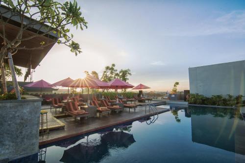 a pool at a resort with chairs and umbrellas at Sevn Legian in Legian
