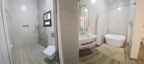 a bathroom with a sink and a shower and a toilet at Roghan Hospitality Inn in Al Ḩamrāʼ