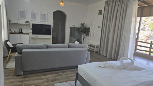 a living room with a gray couch and a kitchen at Roghan Hospitality Inn in Al Ḩamrāʼ
