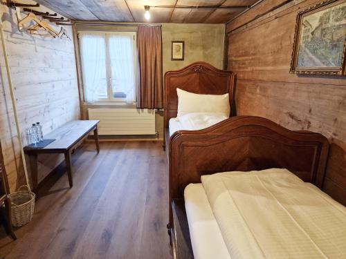 a bedroom with two beds and a table and a window at Drei Könige in Entlebuch
