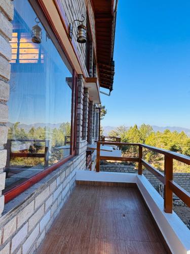 a balcony of a house with a large window at Panchwati Farms Homestay in Almora