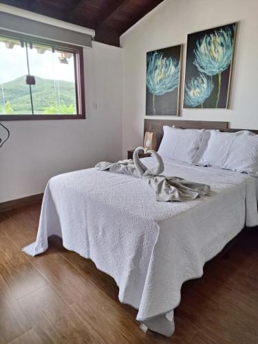 a bedroom with a white bed with a swan on it at Max Suíte in Capitólio