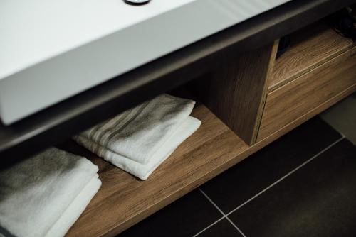 a shelf with towels sitting under a bathroom sink at Hotel Schmachtendorf in Oberhausen