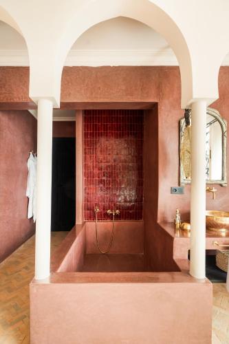 a bathroom with a large tub with a red wall at Riad Dar Acsameda & Spa in Marrakech