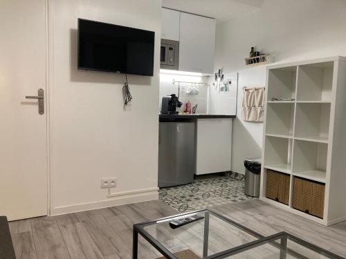 un salon avec une télévision à écran plat sur un mur dans l'établissement Studio Gagny - 2min du RER, à Gagny