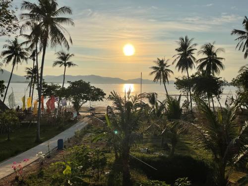 a view of the ocean and palm trees at sunset at Baan Suan Sunset in Ban Laem Sai