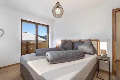 a bedroom with a large white bed with a window at Alpengold - Apartments zum Wohlfühlen in Gröbming