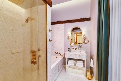 a bathroom with a tub and a sink and a mirror at Maison Barrière Vendôme in Paris