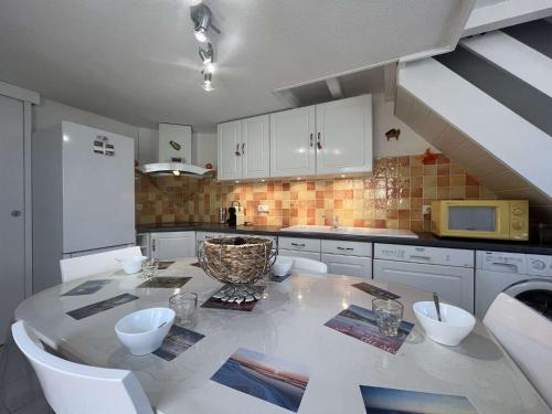 - une cuisine avec une table, des placards blancs et un four micro-ondes dans l'établissement Maison 3 pièces mezzanine - Gruissan GN520-009, à Gruissan
